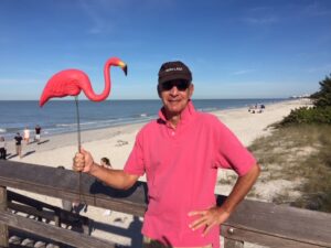 author posing with a plastic flamingo on a FL beach